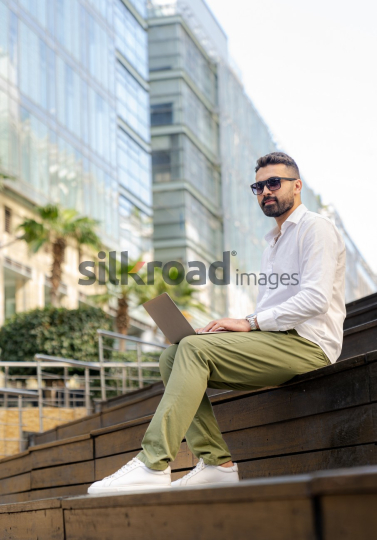 Arab Man Working Outdoors with Laptop in Amman's Abdali Boulevard