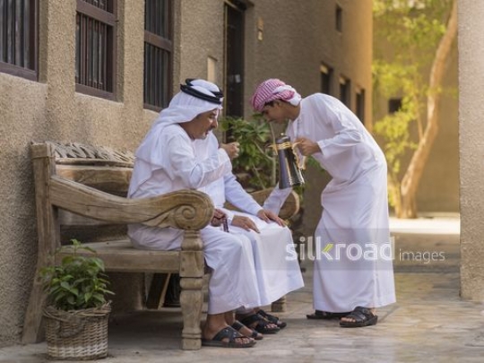 Arab men sitting on the bench having coffee together|-
