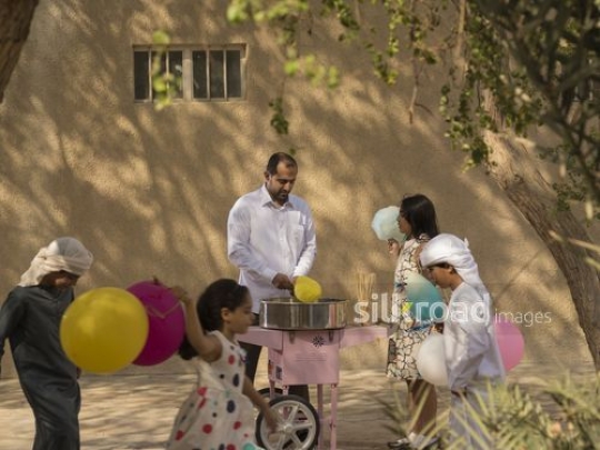 Arab man making cotton candy while the arab kids are playing|-