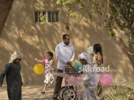 Arab man making cotton candy while the kids are playing|-