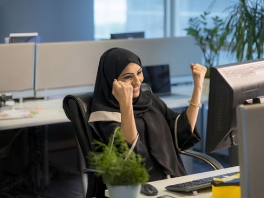 Business woman sitting by her desk excited|
