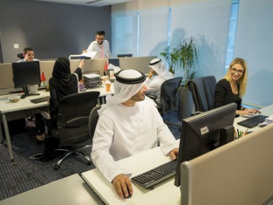 Business people smiling at each other while sitting at their desk|