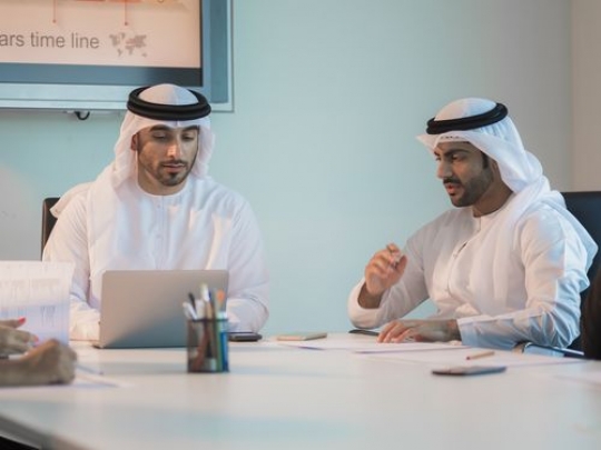 Arab men having a meeting at the office wearing the traditional attire|-