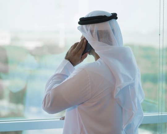 Businessman standing by the window making a phone call|-