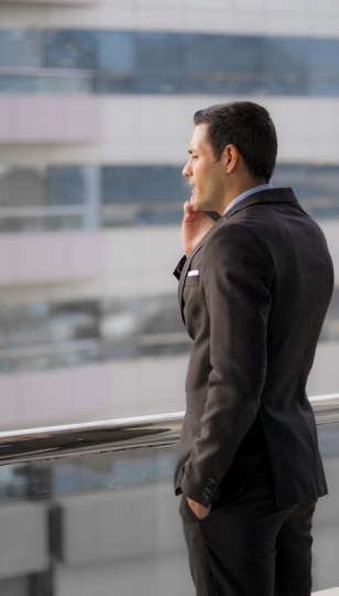 Businessman outside on the balcony having a conversation on the phone|-