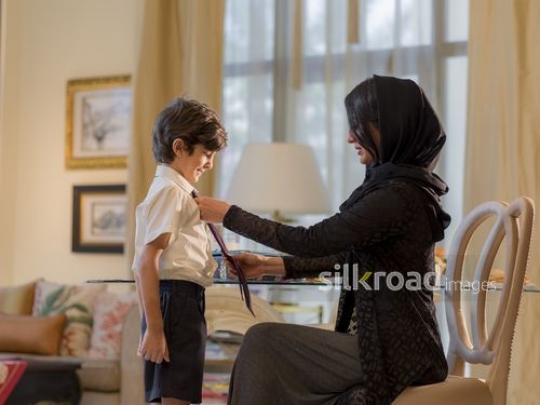 Arab mother getting her son prepared for school|