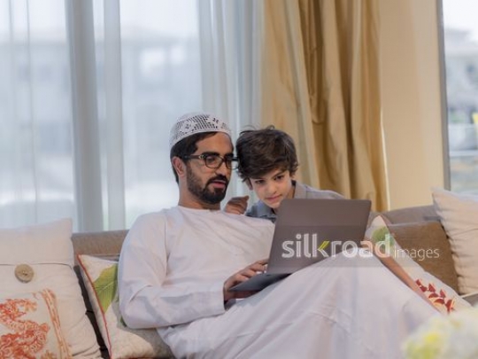 Middle Eastern man and boy sitting together on the couch|