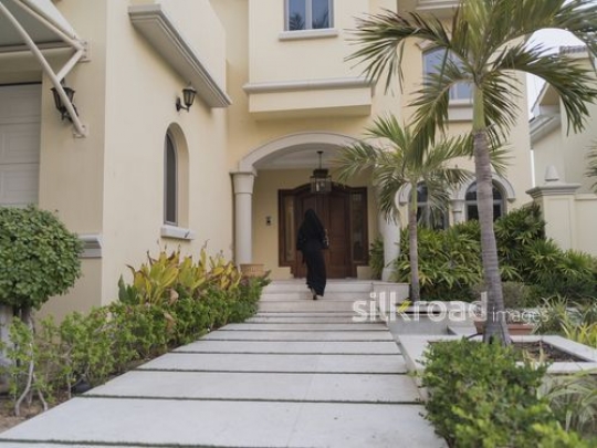 Middle Eastern woman walking towards her house |