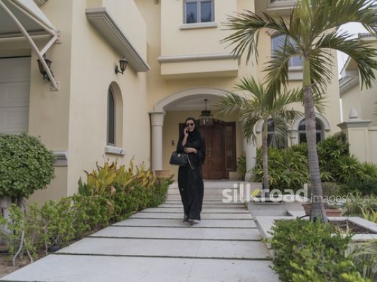 Middle Eastern woman on the phone leaving the house|