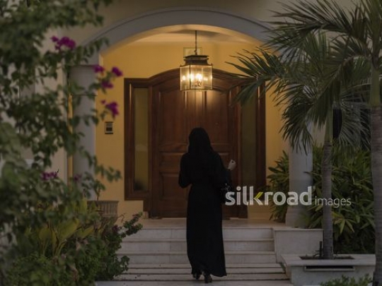 Middle Eastern woman walking towards the house|