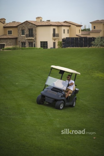 Young Middle Eastern man driving the Golf Cart|-