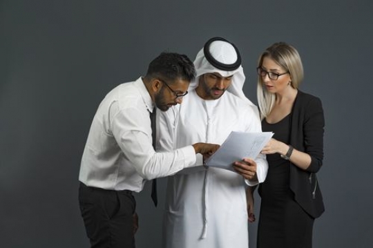 Business woman and business men looking at paper talking to each other|