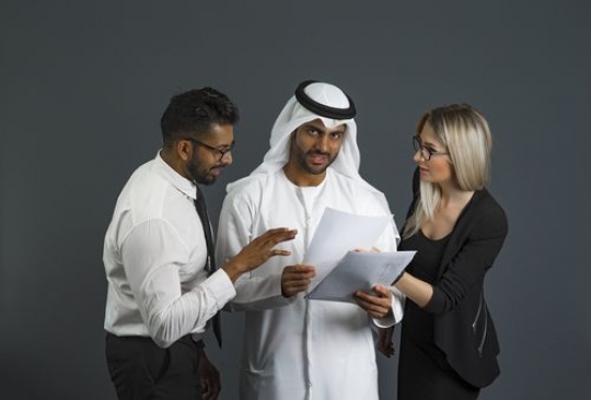 Business people standing and looking at the paper talking to each other|