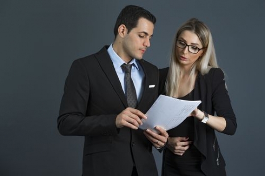 Medium shot of a business woman and business man talking to each other|