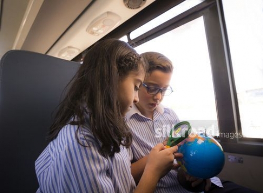 Middle Eastern Kids sitting on the bus together looking at the globe|-