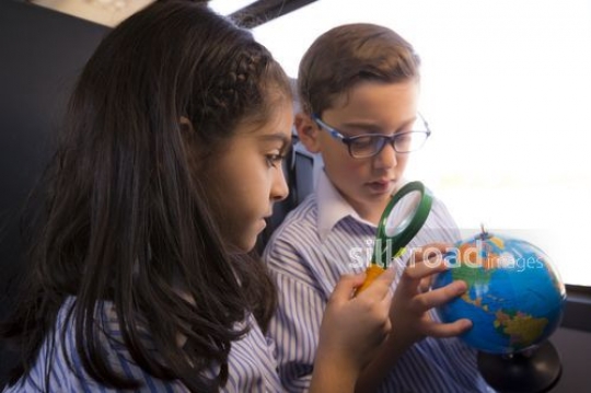 Middle Eastern Kids sitting together on the bus looking at the globe|-