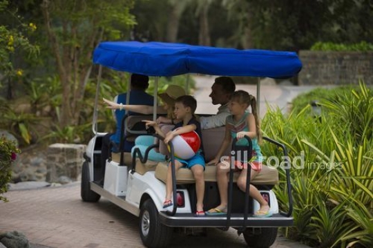 Family on a golf cart at the resort|-