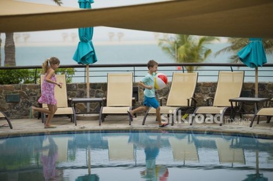 Western siblings running by the pool|-