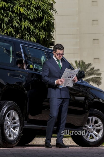 Businessman standing infront of his car reading the newspaper |-