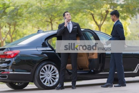 Arab Businessman standing infront of the opened door talking on the phone|