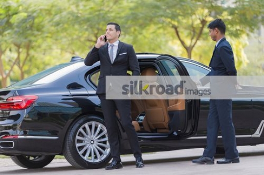 Businessman getting out of the car talking on the phone|