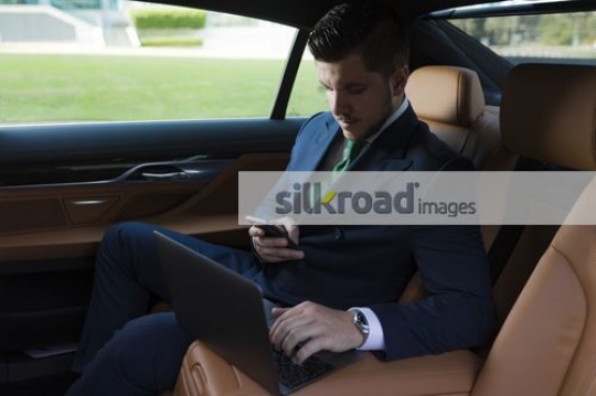 Western Businessman sitting inside of the luxury car doing business|
