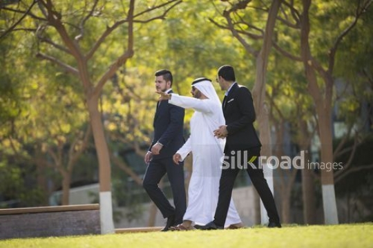 Middle Eastern Businessman pointing at something and his colleagues are walking next to him|-