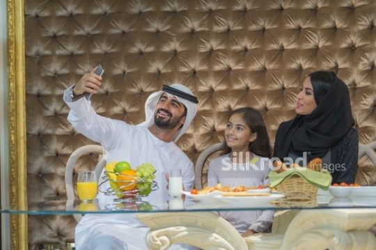 Middle Eastern man taking a s selfie with the woman and young girl |