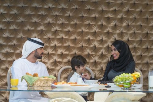 Arab mother fixing her sons tie while talking to her husband|-