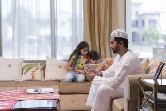 Arab father and their kids sitting on their device|-
