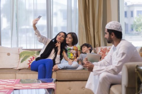 Arab mother taking a photo with the kids while the father is looking at them|-