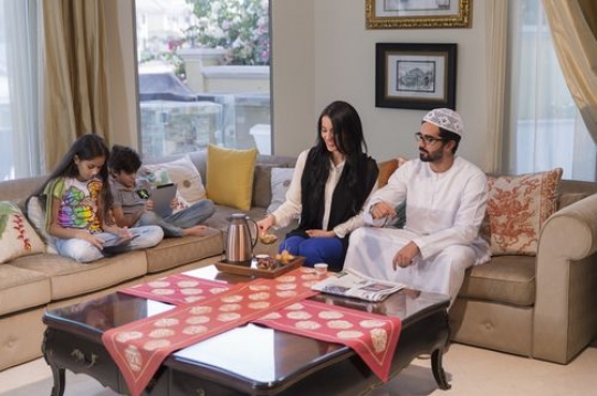 Arab parents sitting together while the kids are on their devices|-