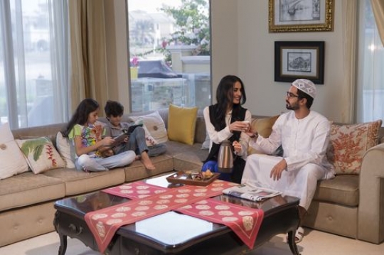 Middle eastern parents sitting together while their kids are on their devices|-