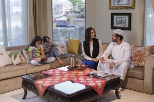 Arab parents sitting with their kids on the couch|-