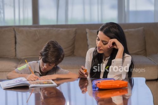 Arab woman helping the young boy with his studies|