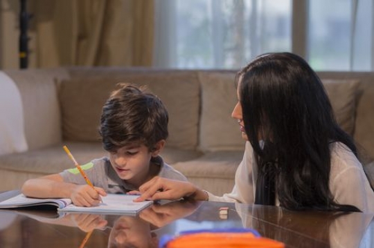 Middle eastern mother helping her son with his school work|-