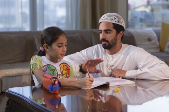 Arab man helping the young girl with her homework|-