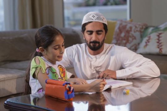 Arab man helping his daughter study|-