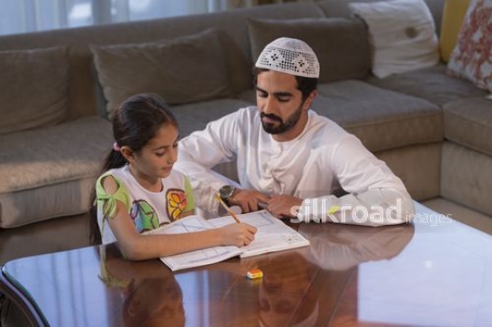 Arab man helping the young girl with her homework |