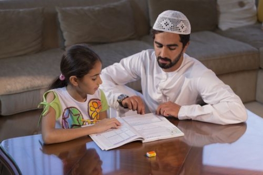 Arab father helping his daughter with her homework |-