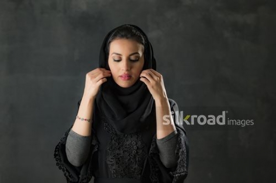 Medium shot of a Middle Eastern woman fixing her shayla|