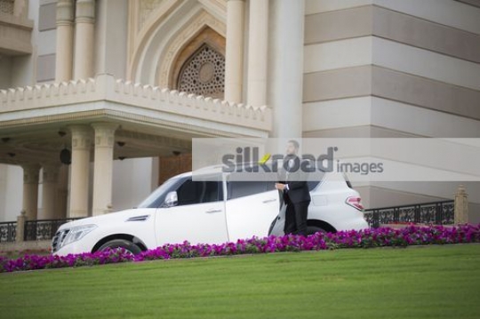 Arab Businessman getting out of the car talking on the phone|