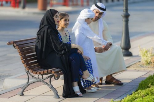 Middle eastern family dressed in traditional attire spending time all together|-