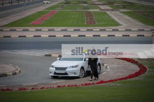 Arab Businesswoman carrying folders and a handbag walking|