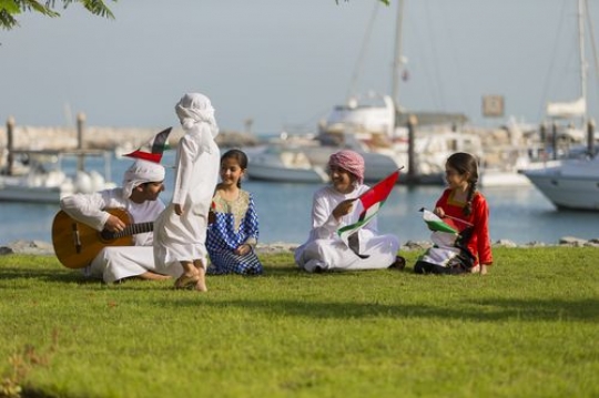 Arab boy walking towards the teenagers and kids to celebrate national day|-