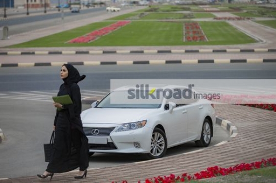 Middle Eastern Businesswoman carrying folders and a bag walking|