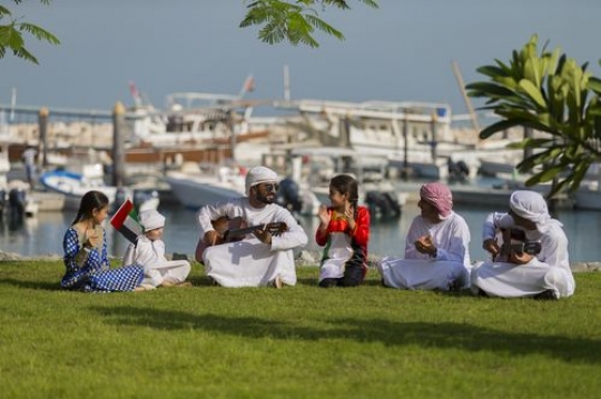 Friends and family celebrating national day while sitting on the grass|-