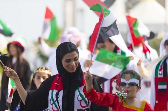 Medium shot of an arab woman and child during a National Day parade|