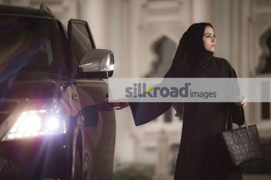 Middle Eastern Businesswoman dressed in the traditional attire closing the car door|