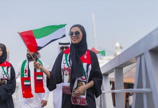 Arab woman walking on the dock dressed in the traditional attire celebrating the UAE National Day|